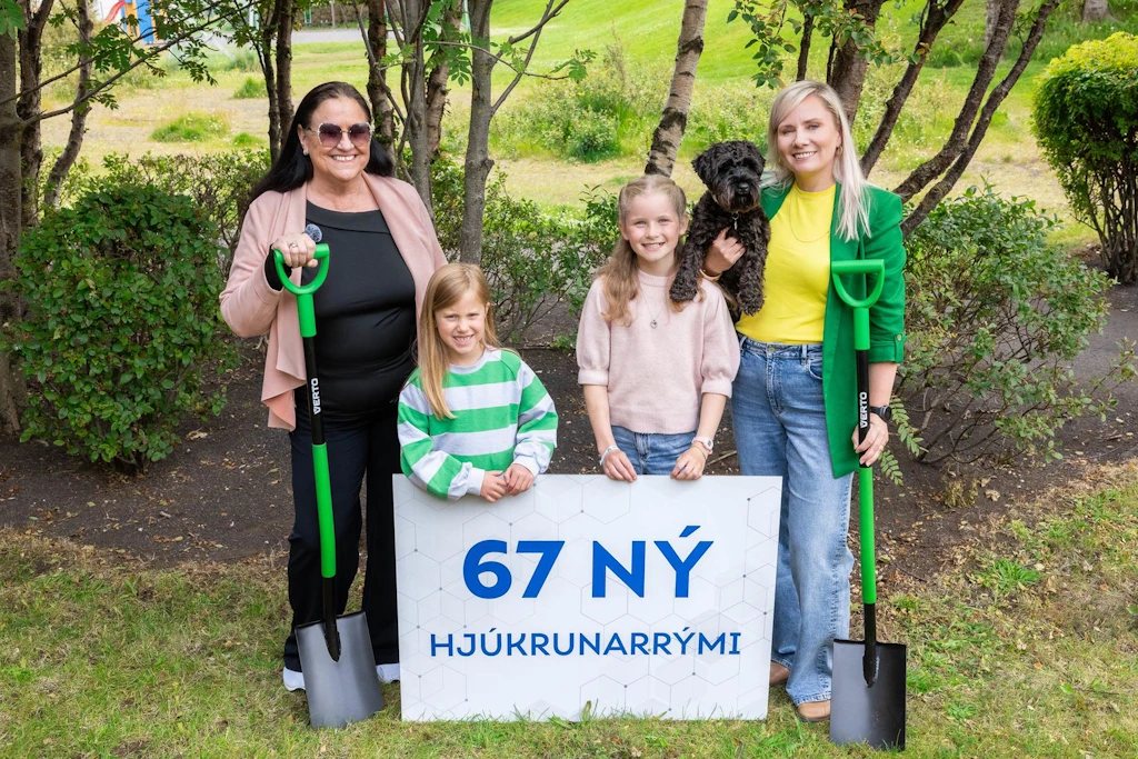 Hópmynd við skiltið „67 ný hjúkrunarrými“